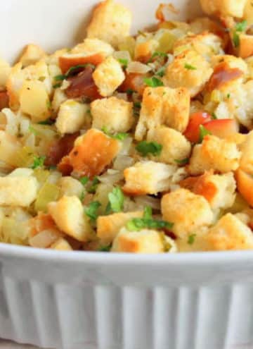 Fluffy stuffing topped with parsley in white casserole dish.