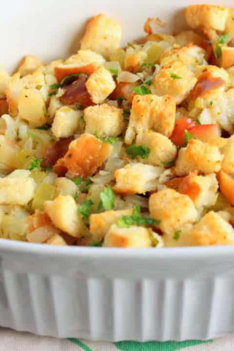 Fluffy stuffing topped with parsley in white casserole dish.