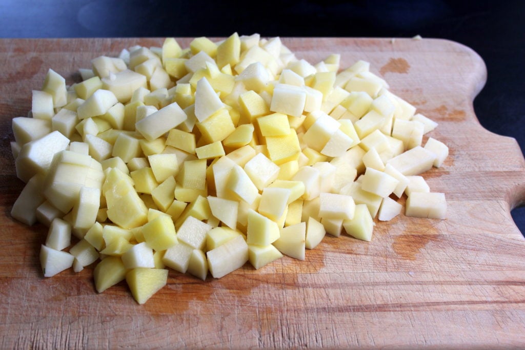Peeled and cubed potatoes on Wooden Board.