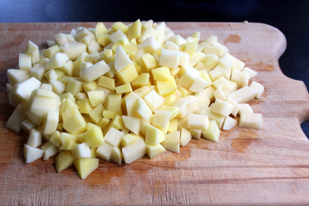 Cubed Potatoes Piled on Wooden Board.