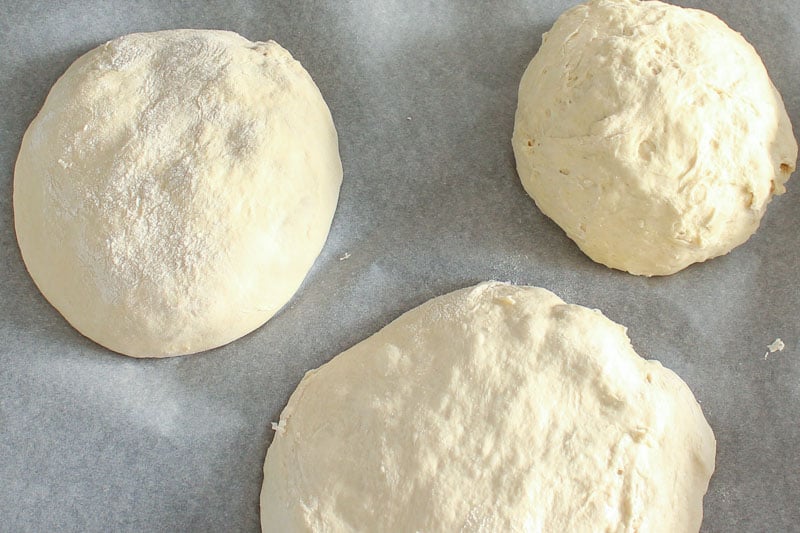Three Balls of Pizza Dough on Parchment Paper.
