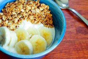 Yogurt, Sliced Banana and Granola in Blue Bowl.