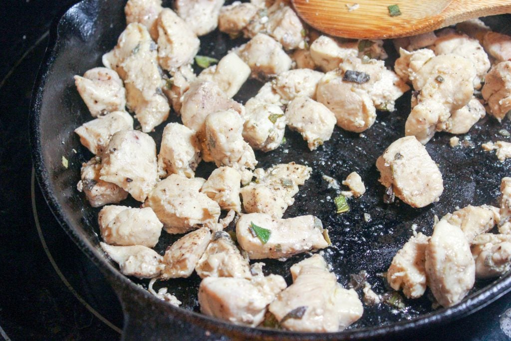 Cubed Chicken frying in cast iron frying pan.