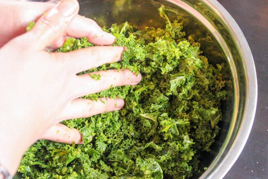 Hands massaging a bowl of kale