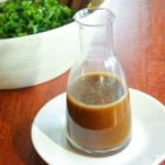 Salad dressing in glass jar on white plate.