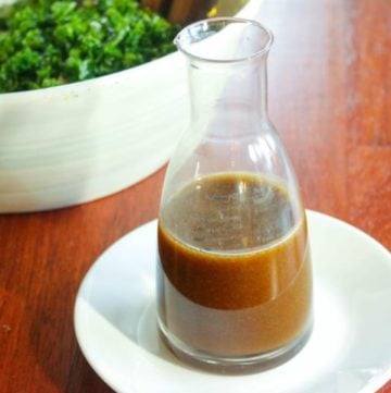 Salad dressing in glass jar on white plate.