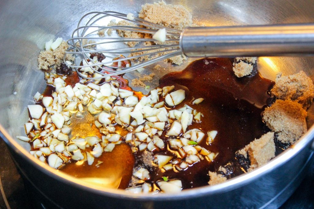 Mixing Garlic, brown sugar and soy sauce in metal bowl.