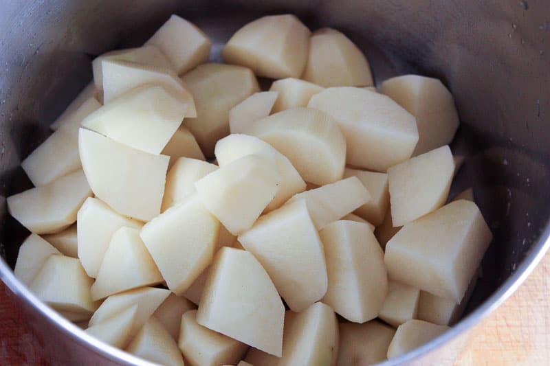 Cubed potatoes in metal pot.