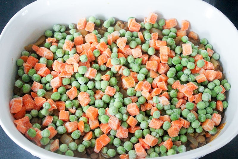 Frozen peas and carrots in White Casserole Dish.