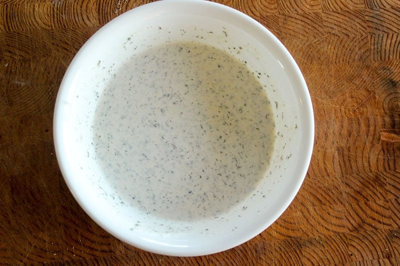 Creamy Ranch Dressing in white bowl on wood background.