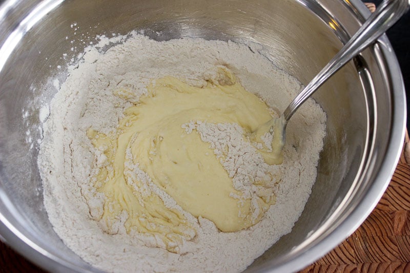 Egg mixture mixed with flour mixture in metal mixing bowl.