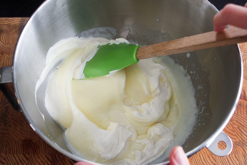Mixing lime juice and whipping cream in metal mixing bowl.