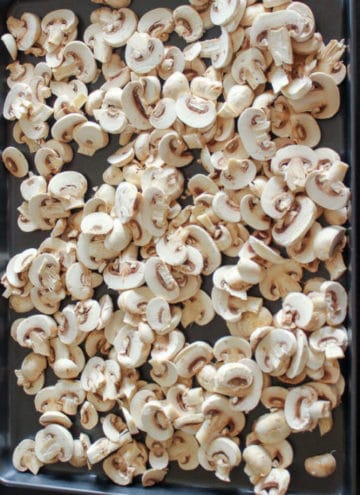 Sliced mushrooms on metal sheet pan.