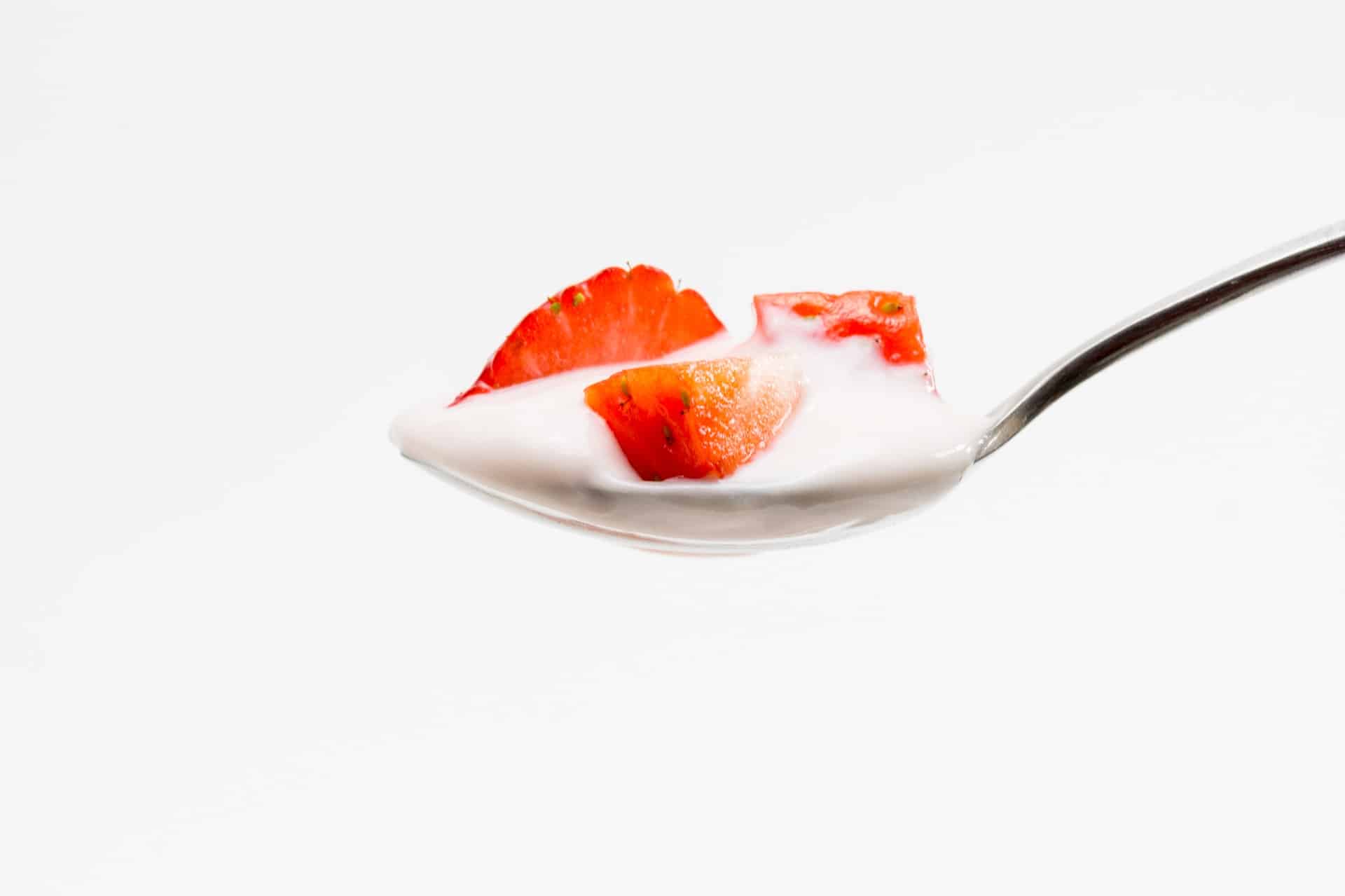 A spoonful of yogurt topped with sliced strawberries.
