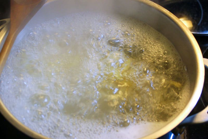 Boiling water in metal pot on stove.