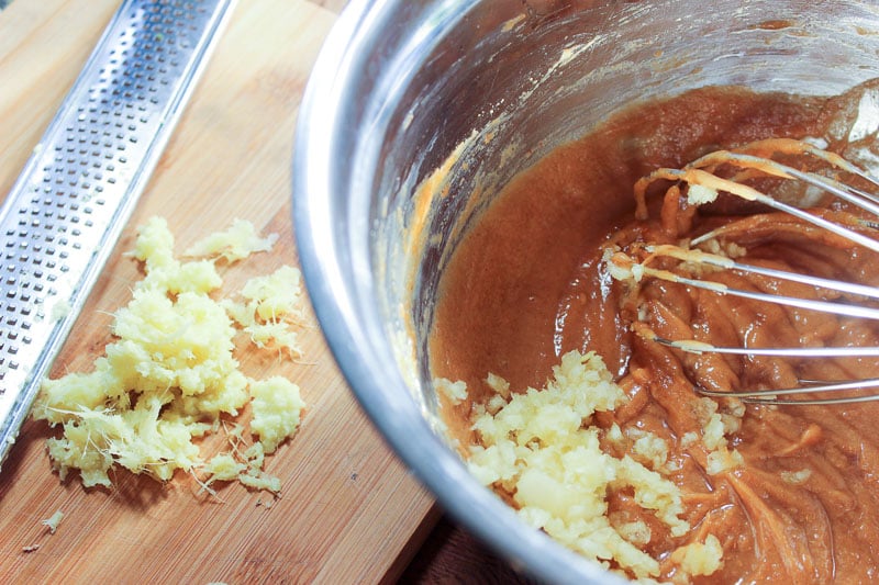 Minced garlic in brown sauce in metal bowl.