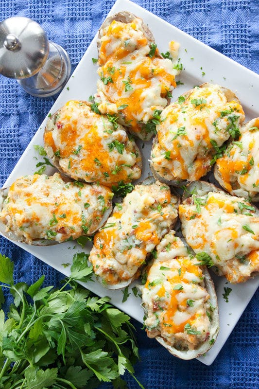 Loaded Twice Baked Potatoes Topped with Cheddar Cheese and Parsley in White Plate.