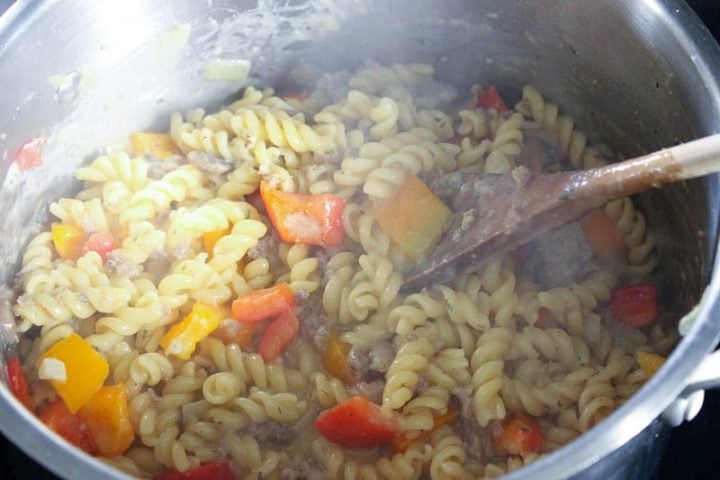 Pasta and vegetables cooking in metal pot.