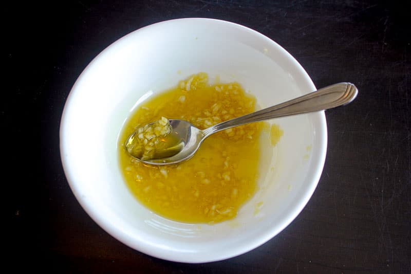 Olive oil and minced garlic in a white bowl.