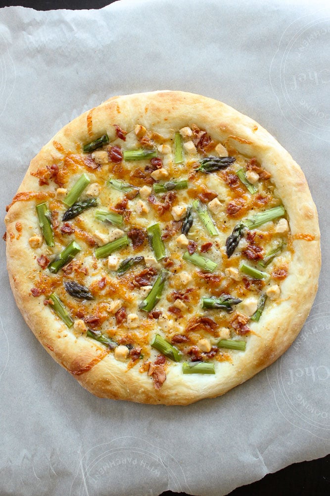 Round Asparagus Bacon Goat Cheese Pizza on Parchment Paper.
