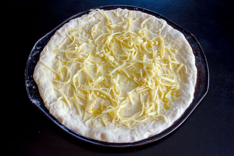 Shredded Mozzarella Cheese on Round Pizza Dough.