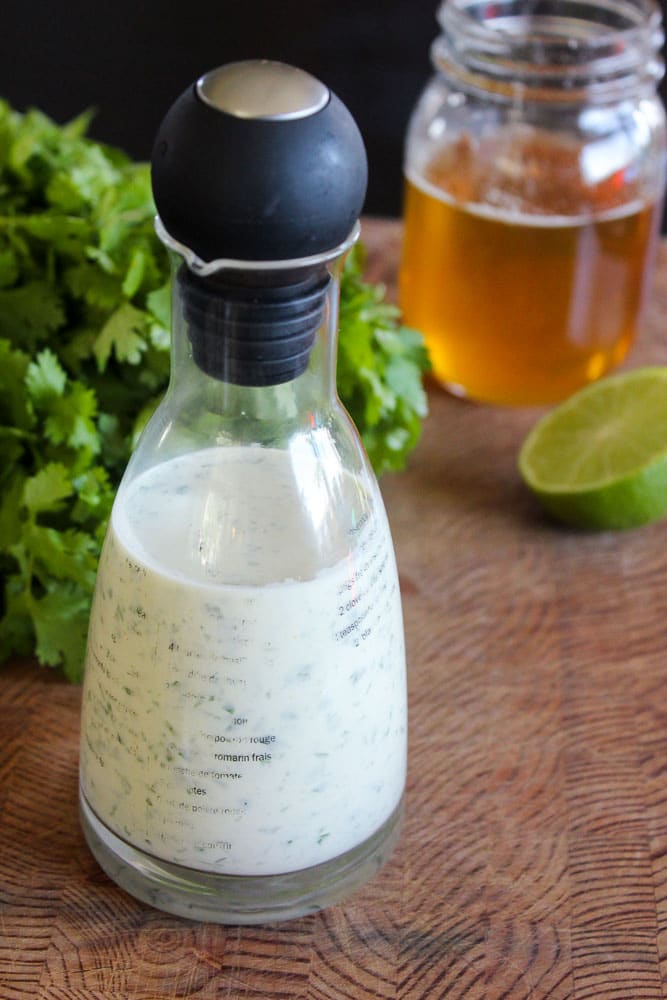 Cilantro Lime Dressing in Glass Jar on Wooden Board.
