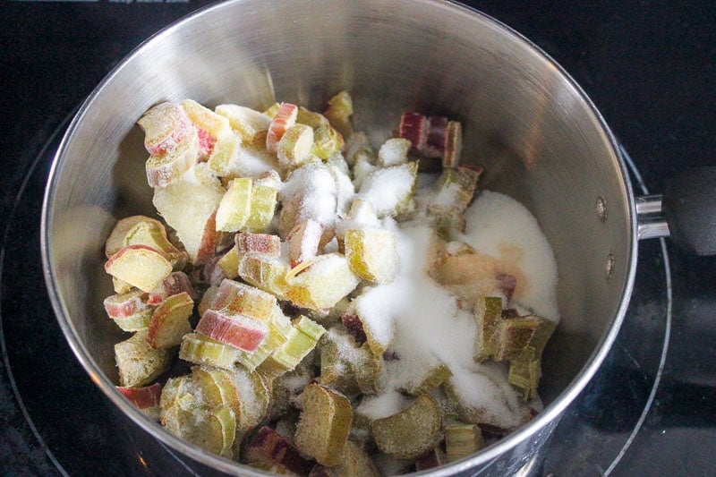 Frozen chopped rhubarb and sugar in metal mixing bowl.