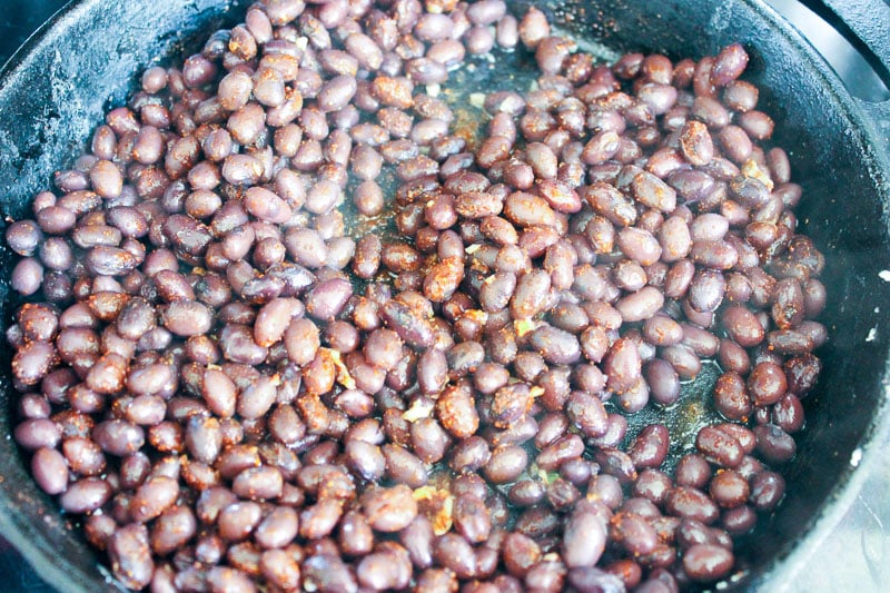 Cooking red beans with spices in cast iron pan.