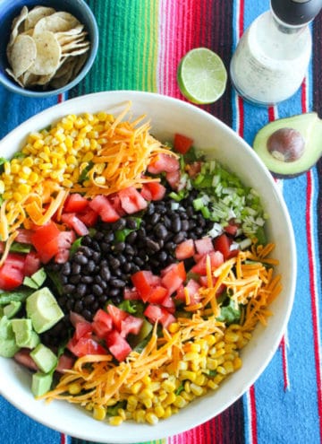 Mexican salad with beans, cheese and vegetables in white bowl.