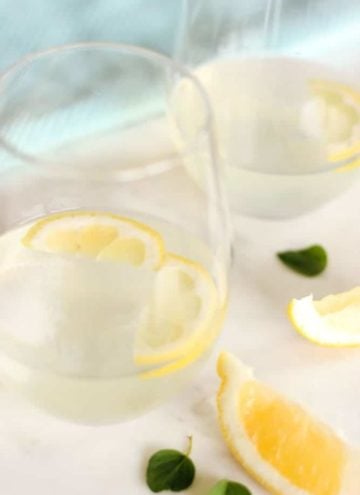 Glass of lemonade with sliced lemons.
