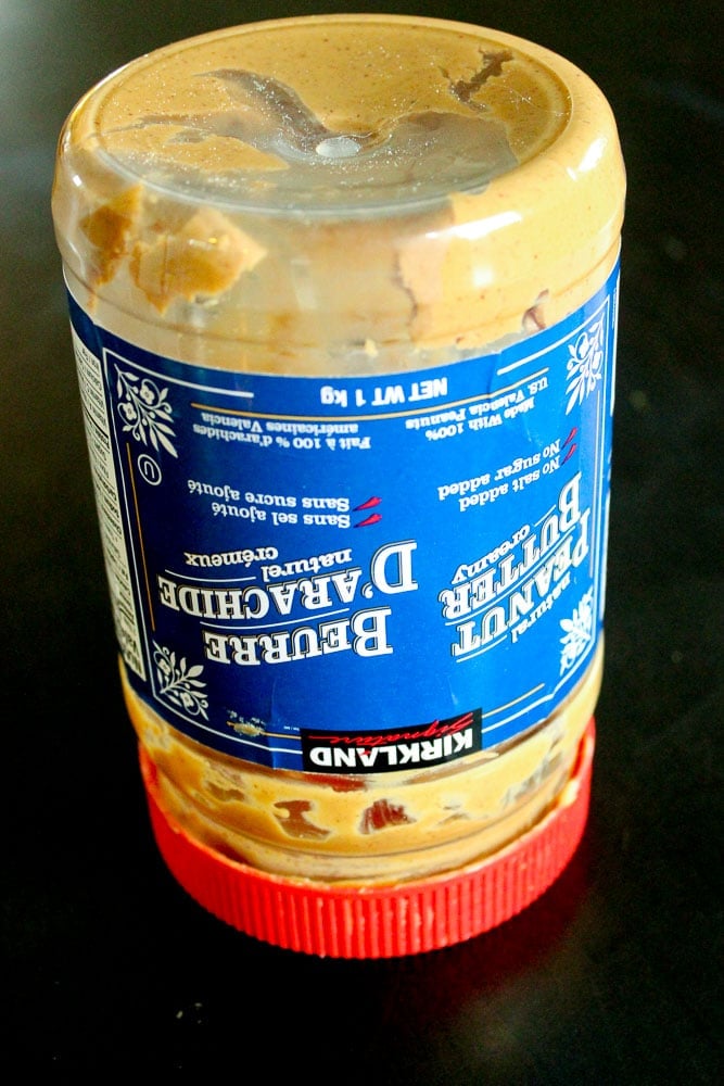 Upside down empty jar of natural peanut on black background.