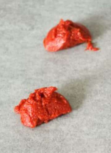 2 scoops of tomato paste on parchment paper.