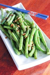 Asian-Style Green Beans and Blue Chopsticks on White Plate.