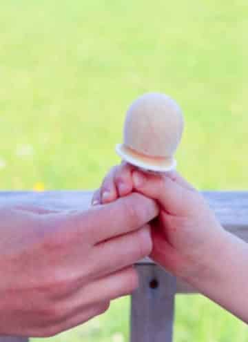 Adult giving child homemade popsicle.