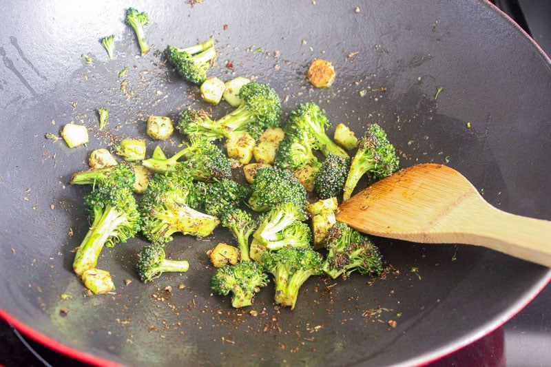 Broccoli and spices in wok on stove.