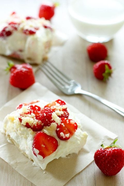 Strawberry shortcake square topped with whipping cream and sliced strawberries.
