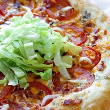 Pizza topped with bacon, lettuce and tomatoes.