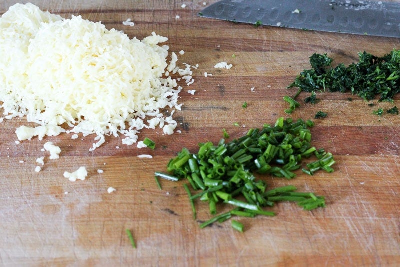 Shredded Cheese, Chopped Parsley and Chives on Wooden Board.