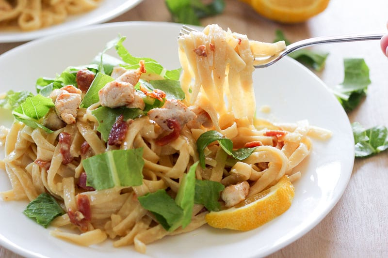 Chicken Caesar Salad Pasta Topped With Shredded Lettuce on White Plate.