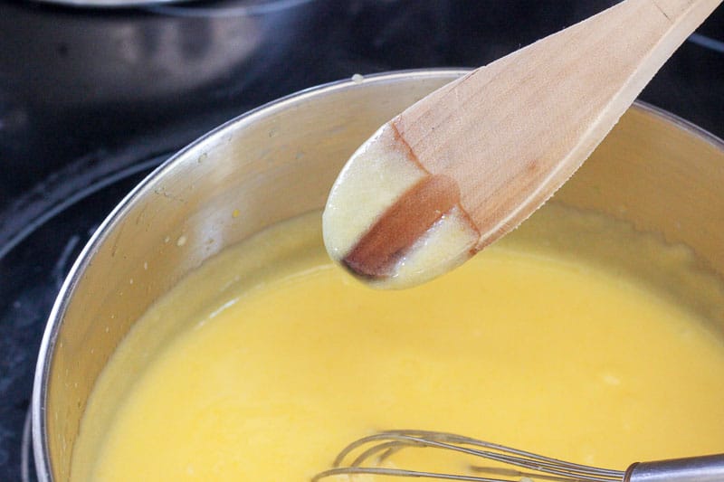 Putting Wooden Spoon Into Lemon Mixture in Metal Pot.