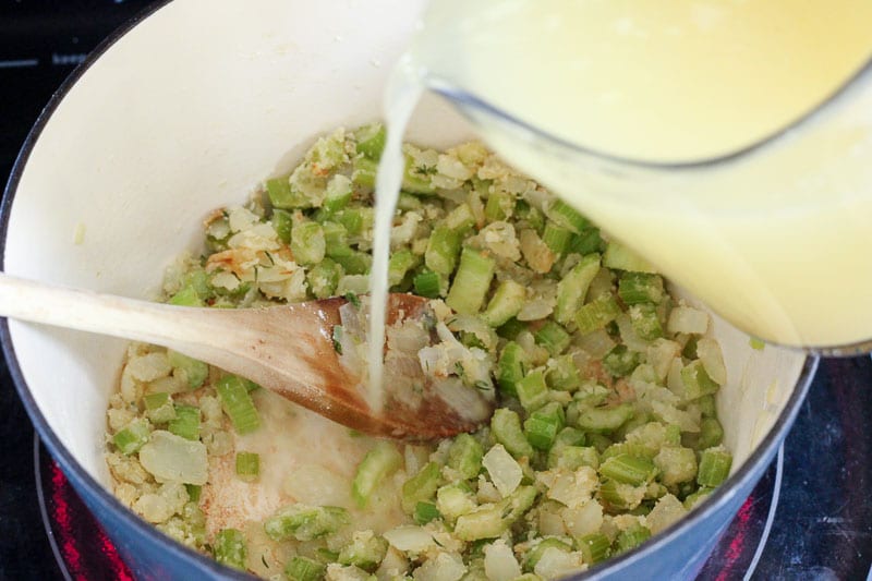 Pouring Chicken Bouillon over Chopped Celery in Blue Pot.
