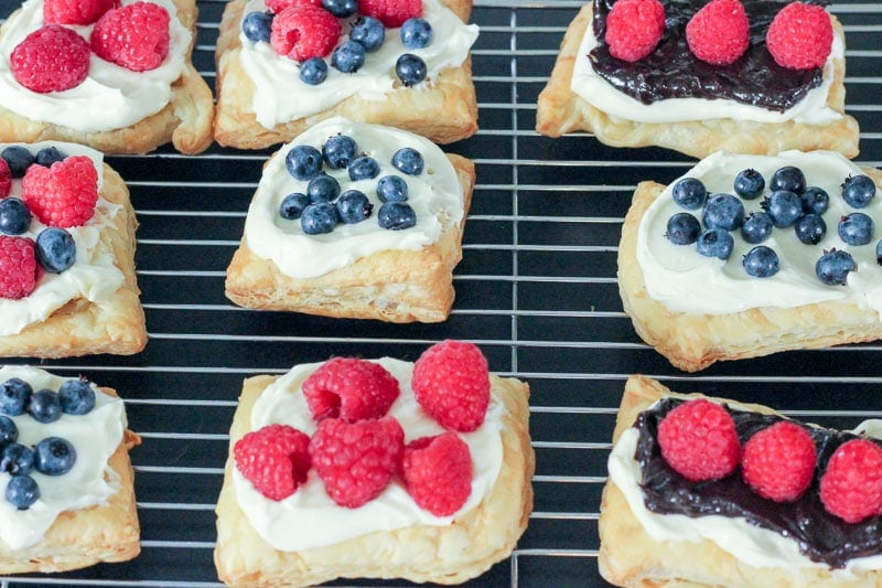 Cream Cheese Pastries topped with Blueberries and Raspberries on Wire Rack.
