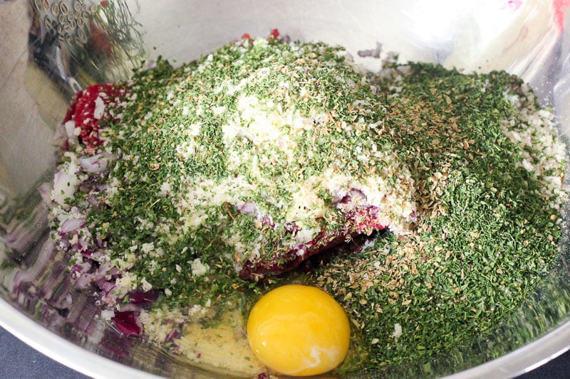 Herbs, Spices and an Egg on Top of Beef in Metal Bowl.