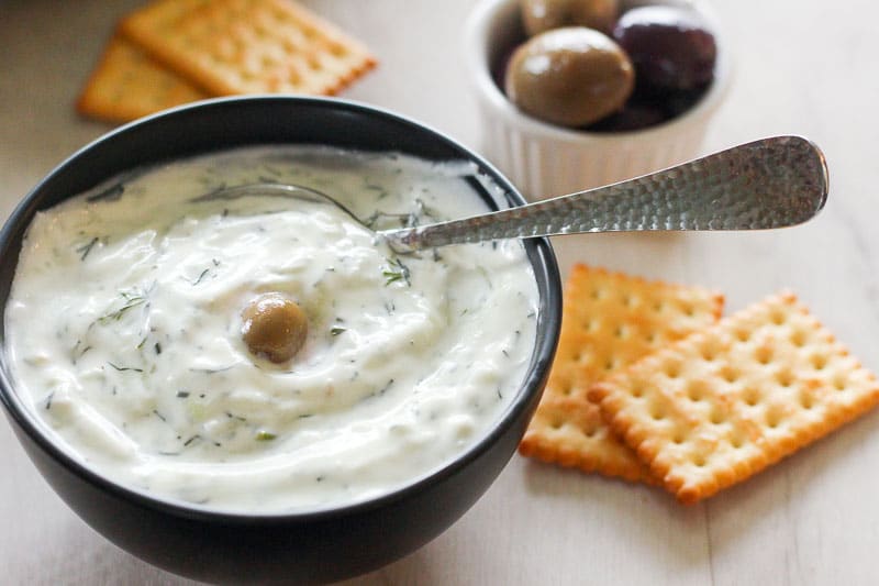 Tzatziki in Black Bowl Topped with an Olive.