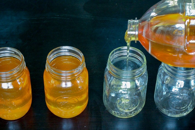 Pouring Honey into Glass Mason Jars.