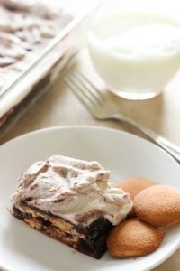 Piece of Chocolate and Vanilla Icebox Cake and three vanilla wafers in small white plate.