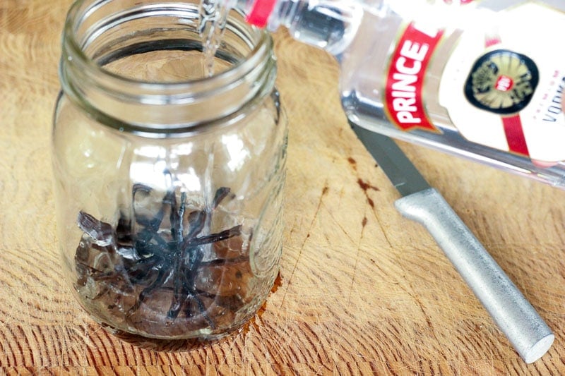 Pouring Vodka into Mason Jar with Vanilla Beans in It.
