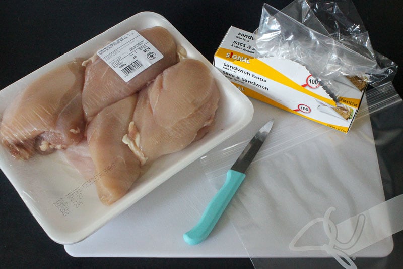 Package of Chicken Breasts, knife and resealable bags on Black Background.