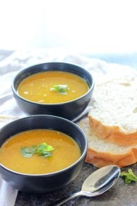 Coconut Curry Carrot Soup topped with Cilantro in Black Bowls.