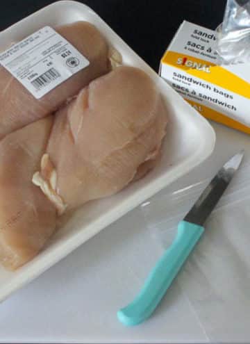 Raw chicken in package, knife and box of plastic bags.